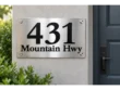 Brushed stainless steel address plaque with raised black 431 numbers and Mountain Hwy lettering beside a blue front door.