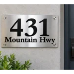 Brushed stainless steel address plaque with raised black 431 numbers and Mountain Hwy lettering beside a blue front door.