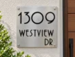 Square Stainless Steel Address Sign with Raised Black Lettering - Square brushed stainless steel address sign with raised black 1309 WESTVIEW DR lettering beside a wooden entrance door.