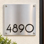 Square Stainless Steel Address Sign with Low-Set Numbers - Square brushed stainless steel address sign with black 4890 numbers positioned near the bottom, beside a wooden door.