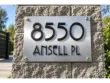 Brushed stainless steel address plaque with raised black 8550 and ANSELL PL lettering mounted on a stone pillar.