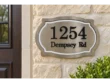 Shaped metallic-coloured address plaque with dark 1254 Dempsey Rd lettering and a light decorative inner border