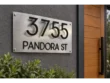 Brushed silver address plaque with floating black 3755 numbers and PANDORA ST lettering beside a wooden entrance door.