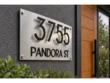 Modern home entrance featuring a brushed silver address sign with floating black house numbers and street lettering.
