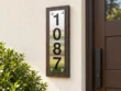 Vertical Stainless Steel Address Sign on Wood Backing - Vertical stainless steel address sign with black 1087 numbers on dark wood backing beside a wooden entrance door.