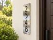 Left-angle view of a brushed stainless steel 2548 number plaque with black numerals and silver corner fixings.