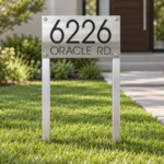 Freestanding stainless steel lawn address sign displaying 6226 Oracle Rd. in black lettering beside a front walkway.