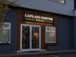 Capilano Maritime Design push through light box sign with warm illuminated lettering on a dark cabinet above white entrance doors.