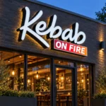 Illuminated white Kebab channel letters with black sides and an ON FIRE sign panel above a restaurant entrance at dusk