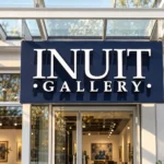 White Inuit Gallery channel letters mounted on a navy backing plate above a glass entrance.