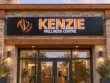 Kenzie Wellness Centre light box sign with orange lettering, white illuminated outlines, and an orange logo on a black cabinet.