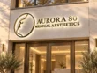 Aurora 80 Medical Aesthetics custom backlit lightbox sign with gold-tone letters and a halo-lit profile logo above glass entrance doors.