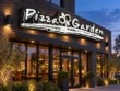 Wider view of the Pizza Garden illuminated script sign above a restaurant entrance and warmly lit windows at dusk.
