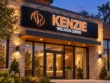 Wider view of the illuminated Kenzie Wellness Centre light box above a glass entrance framed by stone and timber.