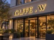 Angled view of the Caffe W backlit channel letter sign showing raised black lettering and warm light behind the characters.