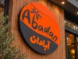 Close-up of the Abadan custom round lightbox sign featuring English and Persian lettering, a palm tree motif, and orange and charcoal graphics.