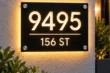 Front view of matte black cut-through illuminated address sign 9495 with 156 ST, warm backlighting and four stainless steel standoffs.