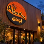 Angled view of the Abadan custom round lightbox sign showing the circular cabinet depth and orange and charcoal branding.