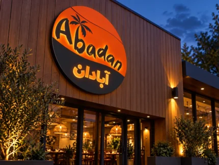 Angled view of the Abadan custom round lightbox sign showing the circular cabinet depth and orange and charcoal branding.