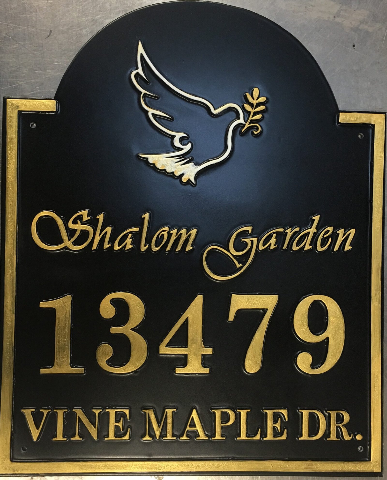 Classic Sign 09 – Black Address Sign with Gold Lettering and Dove Emblem Arched black address sign reading Shalom Garden, 13479 Vine Maple Dr, with gold-coloured lettering, border and a dove carrying an olive branch.