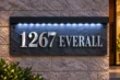 Front view of a natural slate address sign with raised 1267 EVERALL lettering, black corner fixings and LED lights beneath a black hood.