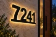 Angled close-up of connected black 7241 house numbers showing their depth and warm backlit halo.