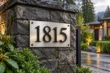 Brushed stainless steel house address sign with black aluminum numbers on stone entrance pillar