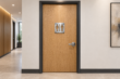 Brushed aluminium washroom sign mounted on an oak door in a condo corridor