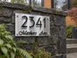 Brushed stainless steel address sign 2341 Mathers Ave mounted on a natural stone wall